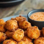 Keto buffalo chicken nuggets with dipping sauce on rustic wooden table