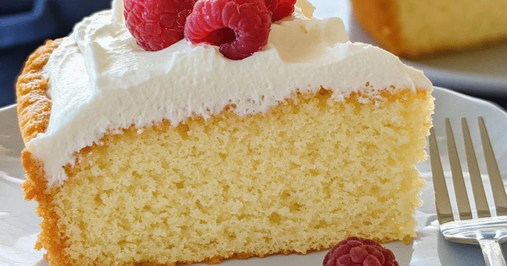 Minimalist Paleo Vanilla Cake slice with whipped frosting and raspberries
