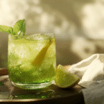 Glass pitcher of green ginger lemonade with lemon and mint