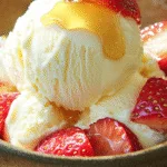 Cottage cheese ice cream with strawberries and honey in a rustic bowl