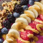 blackberry blueberry banana smoothie bowl with walnuts and peanut butter drizzle