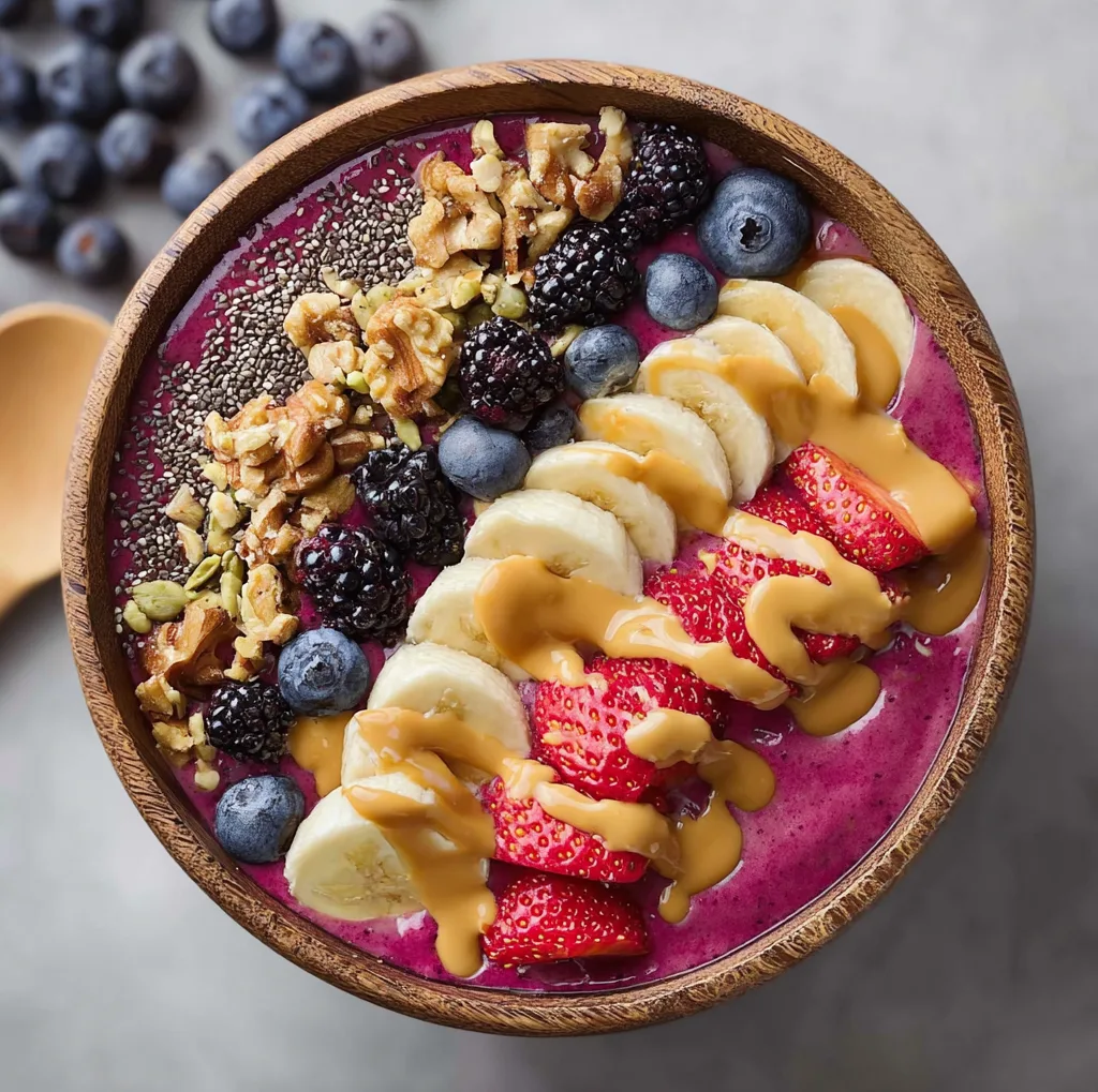 blackberry blueberry banana smoothie bowl with walnuts and peanut butter drizzle